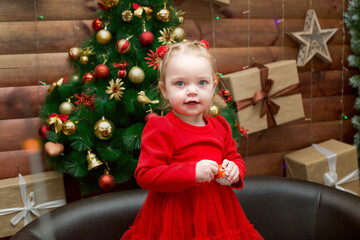 Little girl with a chocolate egg in her hands at the Christmas tree.