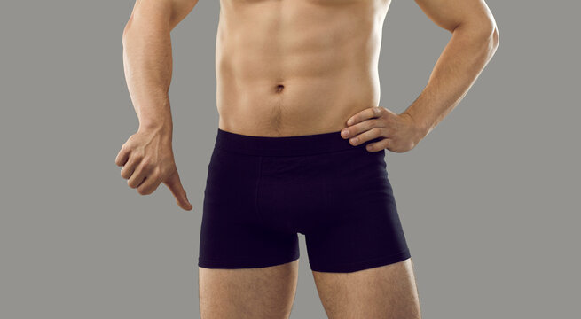 Guy in underwear showing thumbs down standing isolated on grey background. Young male has trouble with intimate matters. Man has difficulty getting erection. Erectile dysfunction and impotence concept