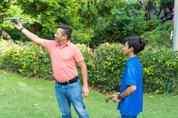 Adult man with son playing with drone in park
