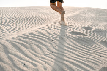 Men's legs walking on a sand in the desert in Qatar, sunset time