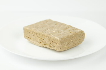 Oriental dessert - halva from sunflower seeds with sugar on a white plate.
