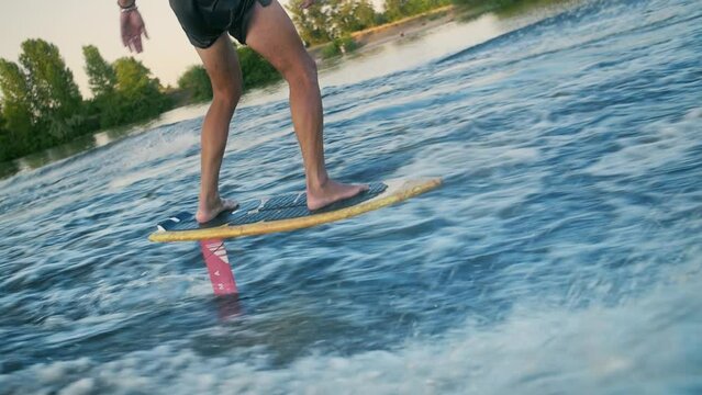Young man riding a foil surf, breaking the ocean waves.Foil Surfing in slow motion.Man standing on a surfboard.