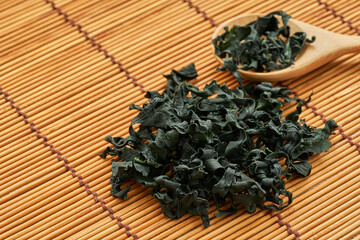 close up dried Laminaria (Kelp) Seaweed in wood spoon on wooden table Background. dried Laminaria or kelp Seaweed on wooden plate Background. konbu, alga, wakame, kombu                             