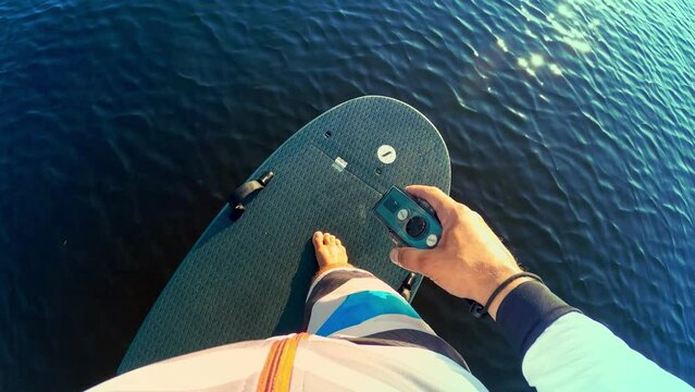 Young man riding an electrofoil.Foil Surfing in first person.Man standing on an electric Board.