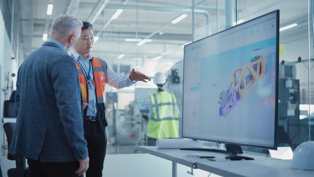 Factory Office Meeting: General Manager Talking with Chief Engineer in a Conference Room with TV Set. Heavy Industry Employees Discussing Modern Hydraulics Mechanism for Industry Equipment.