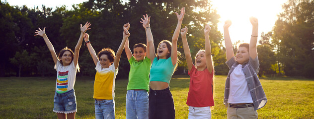 Happy kids emotionally and excitedly exclaim raising their hands during entertainment in summer...