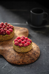 Raspberry tartlets with pistachios and coffee on serving board