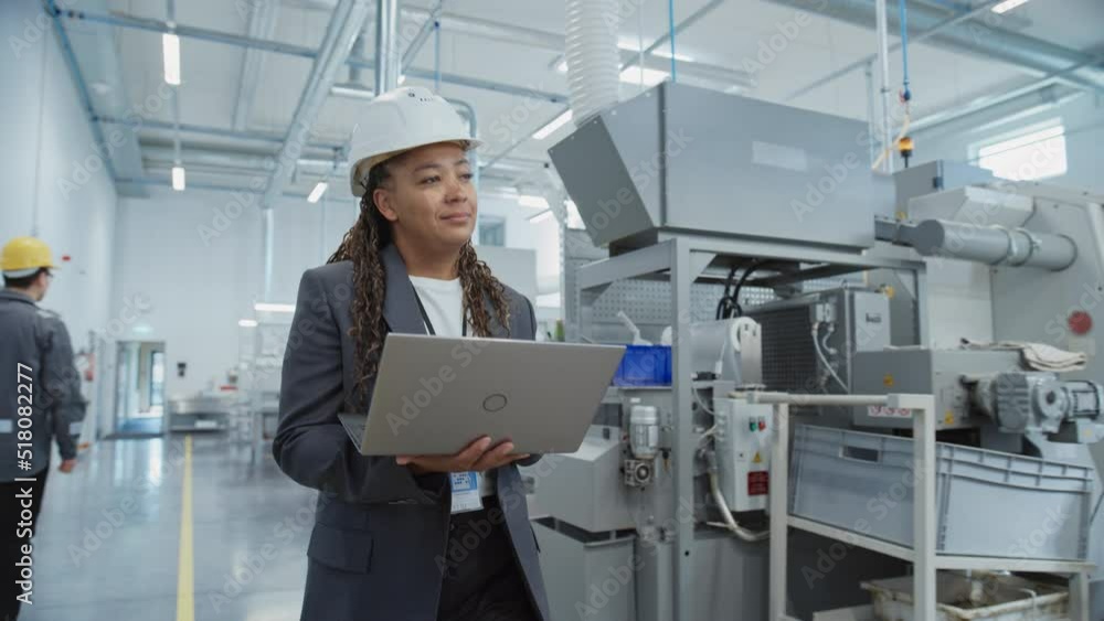 Aufkleber Portrait of a Black Female Engineer in Hard Hat Walking and Using Laptop Computer at Electronic Manufacturing Factory. Technician Working on Daily Tasks and Research and Development Data.