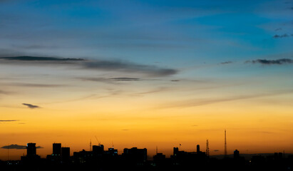 Gives a warm feeling, sunset behind the city building, silhouette city ​​tall buildings, building silhouette again beautiful sky background and freedom concept.