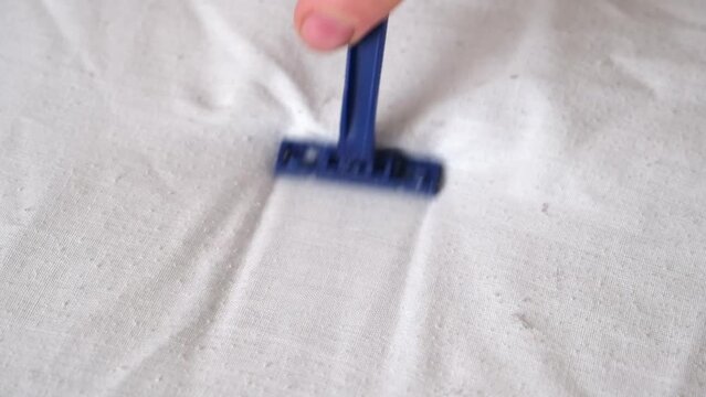 A man removes fabric pills using a disposable shaving machine. A razor for removing pellets.