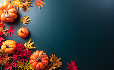 Autumn and thanksgiving decoration concept made from autumn leaves and pumpkin on dark background. Flat lay, top view with copy space.