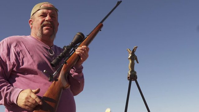 A man uses a bolt action rifle for target practice before deer hunting on the Colorado range.  A spent shell casing is perfectly expelled from the chamber and flies toward the camera
