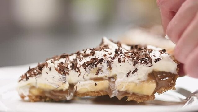 The cook serving Banoffee Pie with bananas, whipped cream, caramel, and chocolate.