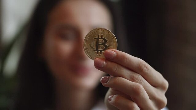 Woman hand holding bitcoin and phone Mining bitcoins from websites on mobile phone concept