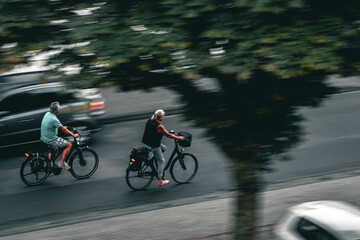Obraz na płótnie Canvas Two people riding bikes on the street.