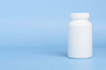 One white blank plastic medical pill or supplement bottle on blue background with copy-space - 518086449