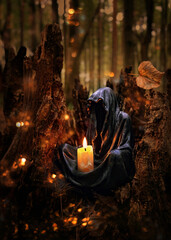 Magician mysterious black cloaked figure, Grim Reaper, Death candlestick with burning candle in...