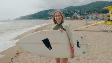 Happy smiling authentic young woman with surfboard look at camera, smile confident and giggle. Summertime adventure, vacation destination lifestyle of surfing in California vibes