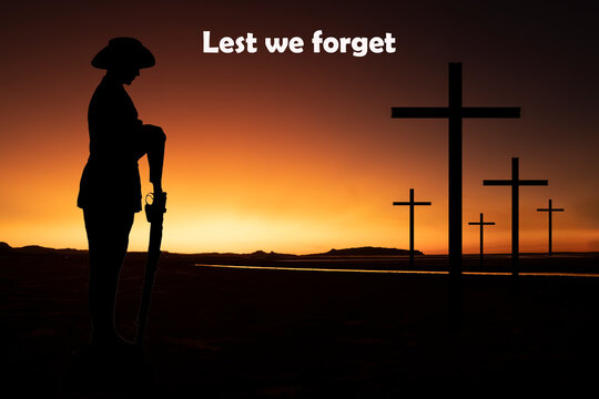 Silhouette of an Australian soldier with arms reversed against a golden sunrise with crosses in the background. Anzac Day concept.