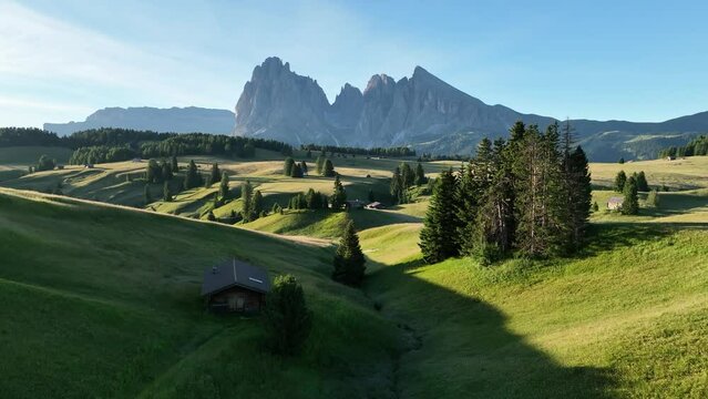 Aerial view of Seiser Alm plateau with traditional wooden mountain cottages on the meadows in Dolomites mountains in Italy. Morning drone shot of idyllic Alpe di Suisi blooming meadow in South Tyrol.
