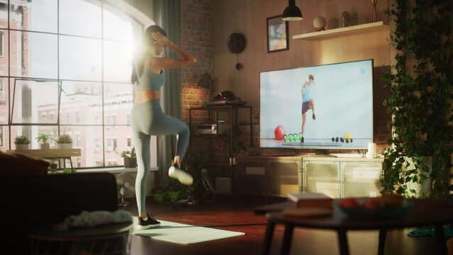 Active Girl Watching Personal Trainer through Online Video Tutorial while Training at Home. Strong Athletic Fit Woman Using Technology, Streaming Fitness for Virtual Training Workout Service