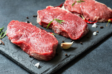 Raw beef steak meat on stone board with thyme and peppers, butcher concept