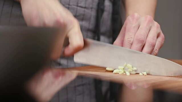 Cutting of garlic on a wooden cutting board, slow motion.