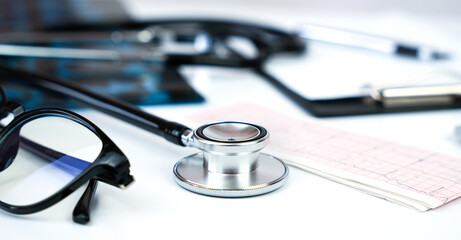 Banner. Doctor's workplace with stethoscope, clipboard, glasses and pills. Close-up. Selective focus.