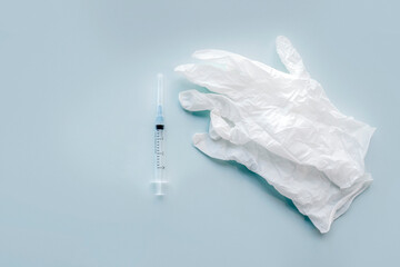 Medical equipment: gloves and syringe. Top view flat lay on gray background. Copy space.