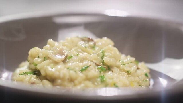 Serving of risotto with mushroom in a plate, slow motion.