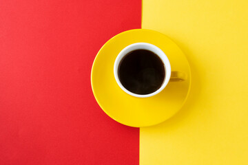黄色と赤の紙の上の黄色のコーヒーカップのコーヒー