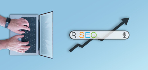 SEO concept, top down view of search bar and person using laptop computer against blue background