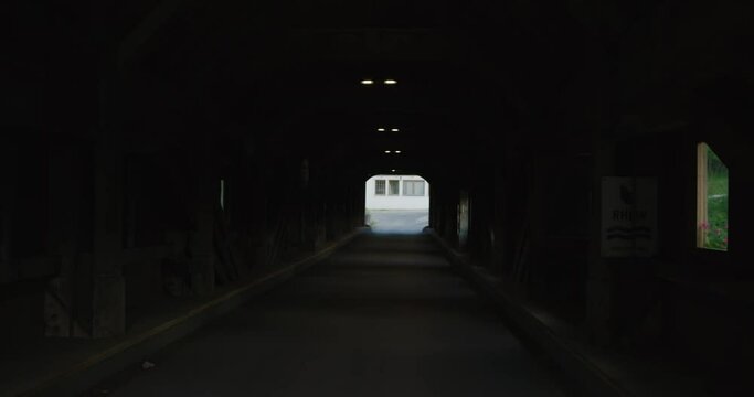 POV of entering an old strange dreamlike warping dark tunnel bridge in Switzerland