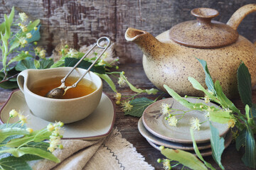 Cup of herbal limeleaf tea with linden flowers on old wooden background