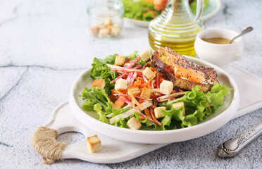 Lettuce salad with red fish, raw vegetables and croutons. Red fish sandwich with rye bread, poppy seeds and mustard sauce