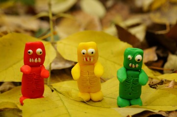 Colorful figures of funny zombies on the background of autumn leaves.