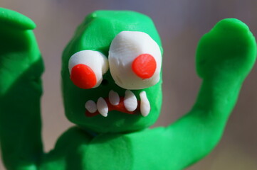 The zombie figurine is trying to scare. Funny monster made of plasticine.