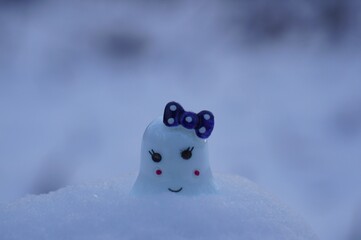 A toy ghost on a background of white snow. A fairy-tale character. Ideas for Halloween.