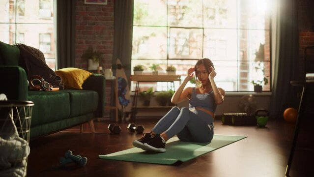 Portrait of a Beautiful Athletic Asian Woman Does ABS Crunches Exercises, Workout, Yoga, Stretching, Training at Home. Sunny Apartment with Positive Smiling Healthy Woman Staying Mindful. 