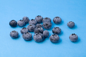 Organic blueberries in glass bowl on blue background, front view. Concept of vegan, freshness, natural food