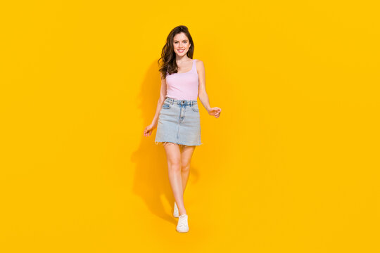 Full length body size view of attractive cheerful girl walking straight isolated over vibrant yellow color background