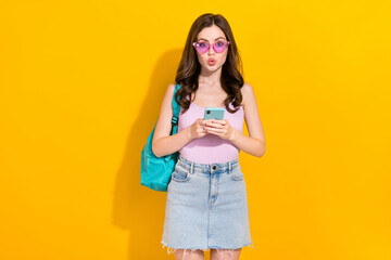 Portrait of impressed pretty girl hold telephone pouted lips isolated on yellow color background