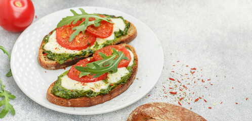 Delicious black rye bread sandwiches.with pesto, buratta cheese or mozzarella, tomatoes and fresh arugula. Brunch. Mediterranean cuisine. Selective focus