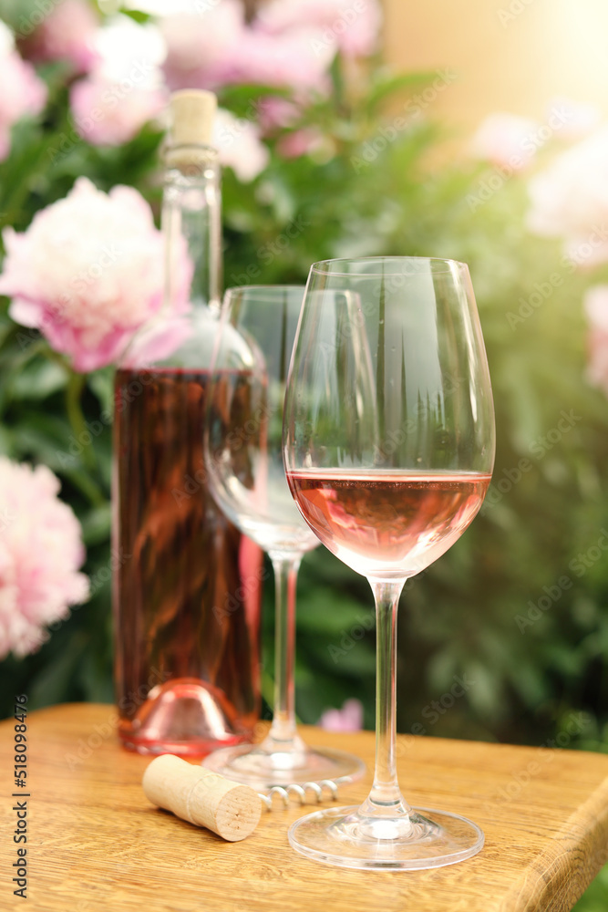 Canvas Prints Glasses and bottle with rose wine on wooden table near beautiful peonies