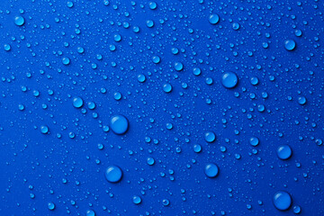 Water drops on blue background, top view