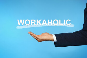 Businessman and word Workaholic on light blue background, closeup