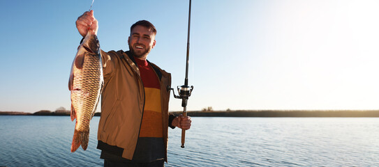 Fisherman holding fishing rod and catch at riverside, space for text. Banner design