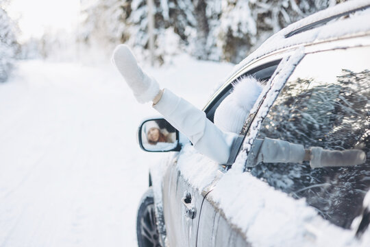 Teenager Girl Looking Out Of Car Window Traveling In Winter Snowy Forest. Road Trip Adventure And Local Travel Concept. Happy Child Enjoying Car Ride. Christmas Winter Holidays And New Year Vacation