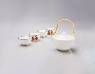 Tea kit with ceramic tea kettle and four cups, with oriental illustration, isolated on white