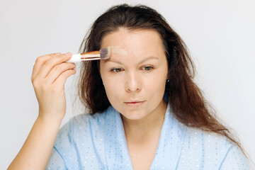 The girl applies a tonal corrective cream on a problematic pigmentation face.